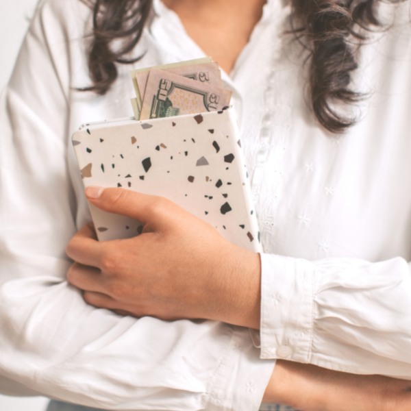 Woman holding notebook with cash inside.