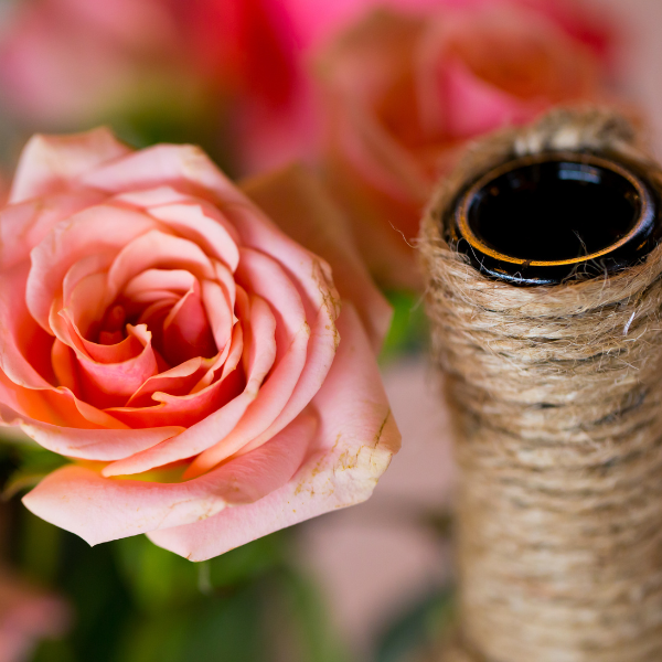 Close up of a diy wedding decor pieces, silk flower and a roll of twine.